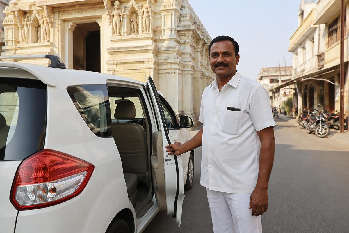 Professional driver in uniform opening the car door for guests in Shirdi